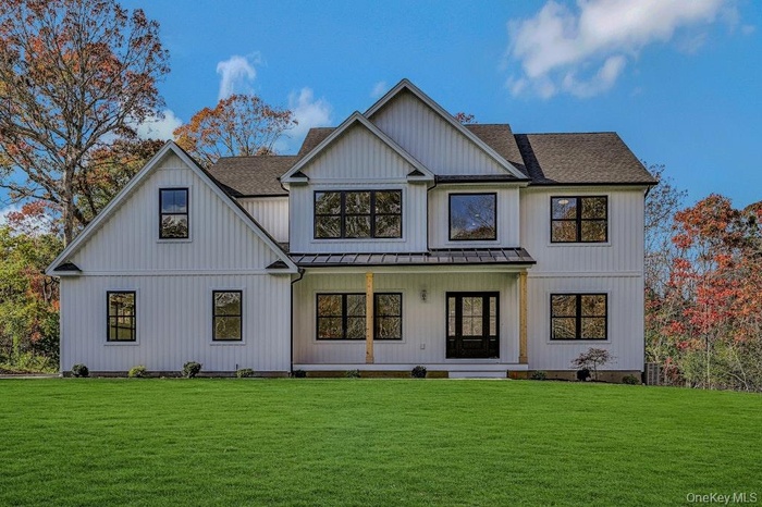 Back of house featuring a lawn, roof with shingles, and a porch
