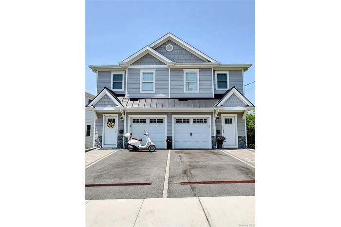 View of front of home with stone siding, a standing seam roof, driveway, and a metal roof