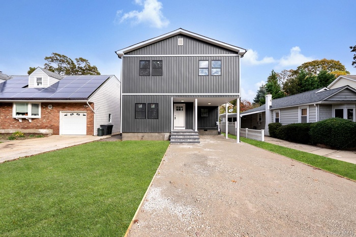 View of front of house featuring concrete driveway, a front yard, and board and batten siding