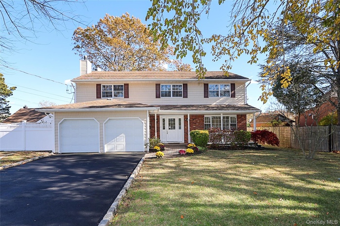 Traditional home featuring asphalt driveway, a chimney, and brick siding