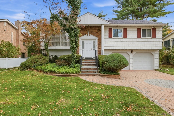 Raised ranch featuring decorative driveway and a garage