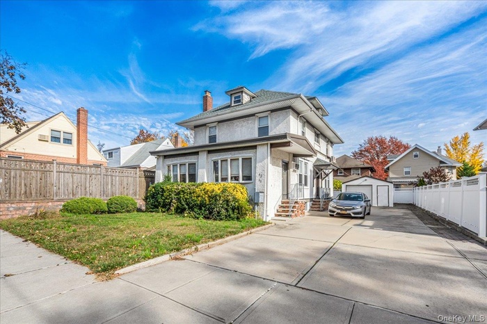 Traditional style home featuring stucco siding, an outbuilding, a detached garage, and a chimney