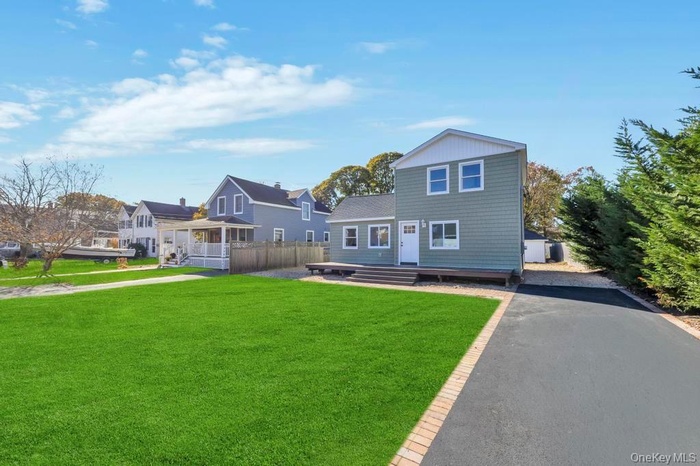 View of front facade with driveway and a wooden deck