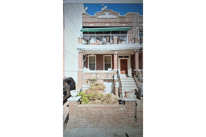 View of front of home with brick siding and a balcony