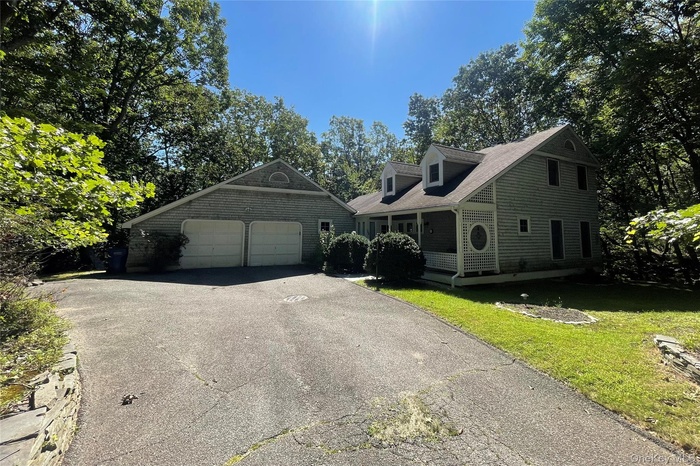 Cape cod-style house with a front yard, driveway, and a shingled roof