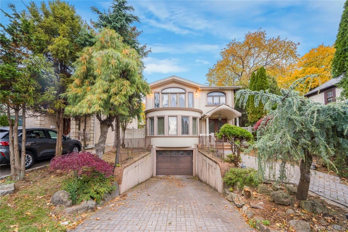 View of front of home with stucco siding, decorative driveway, and a garage