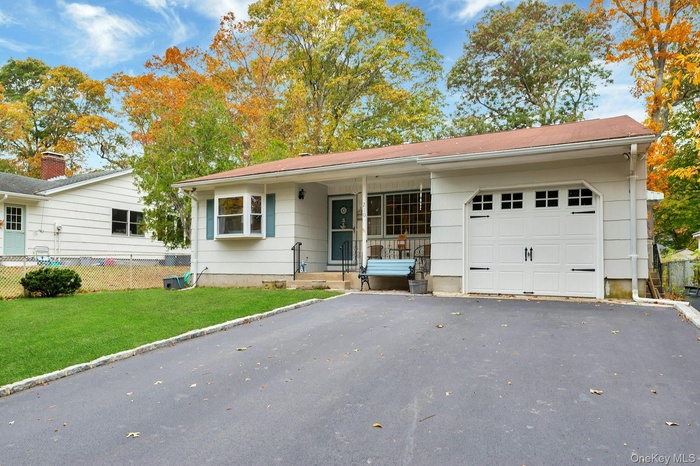 Ranch-style home featuring asphalt driveway, covered porch, and an attached garage