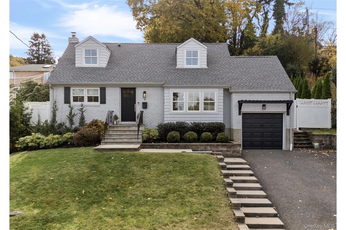Cape Cod style home featuring, vinyl siding, asphalt driveway, attached garage.