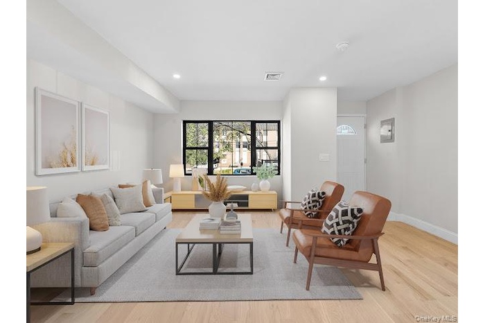 Living area featuring light wood-style floors, recessed lighting, and electric panel