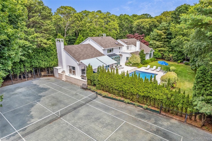 Aerial view of property and surrounding area with a heavily wooded area and a pool