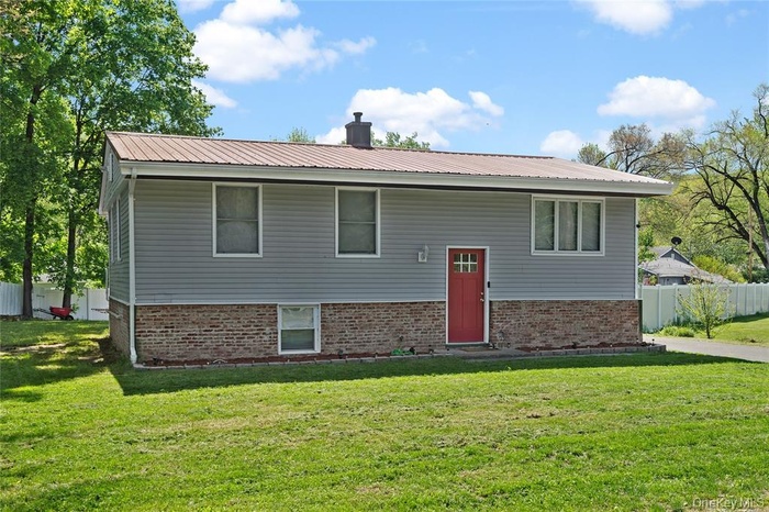 View of front of home with a metal roof, a chimney, and brick siding