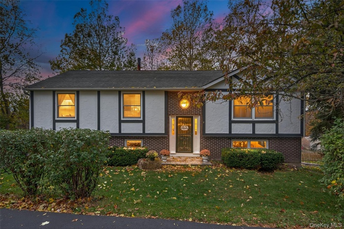View of front of house with brick siding, stucco siding, and a lawn