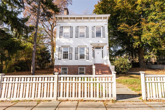 Italianate home with a fenced front yard and a chimney