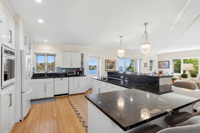 Kitchen featuring white appliances, plenty of natural light, open shelves, a kitchen bar, and recessed lighting