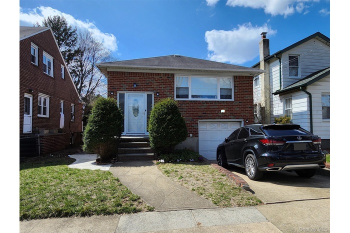 View of front of property featuring an attached garage, concrete driveway, and brick siding