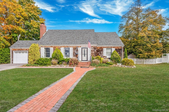 Cape cod home featuring a garage, roof with shingles, a chimney, and driveway