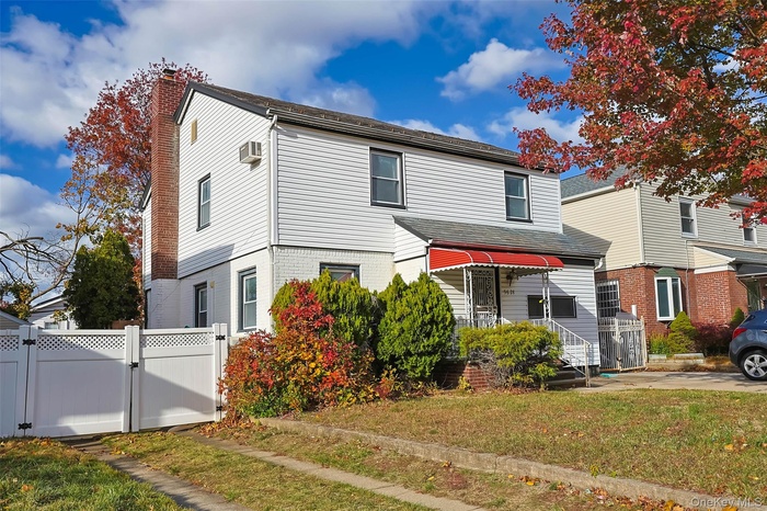 Traditional-style house featuring a gate, brick siding, and a chimney