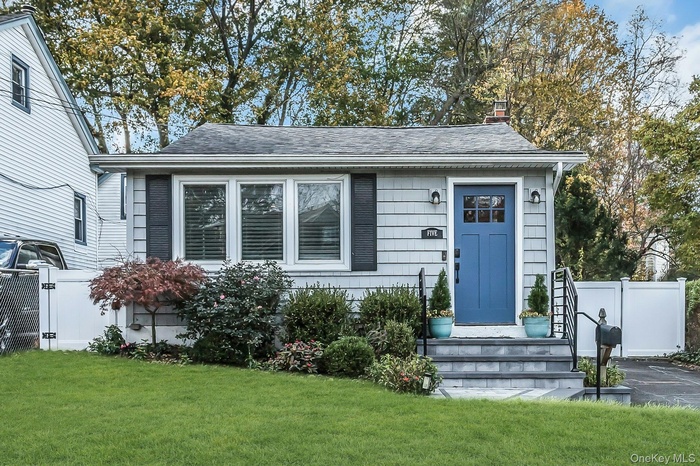 View of front of property with a gate, roof with shingles, and a chimney