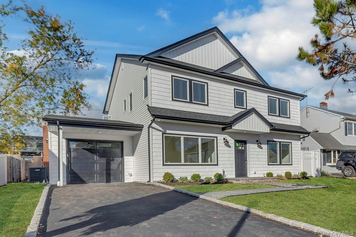 View of front facade featuring asphalt driveway, a garage, board and batten siding, and roof with shingles