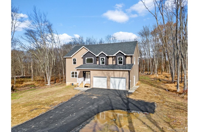 Traditional home with asphalt driveway, a garage, a shingled roof, and a front yard