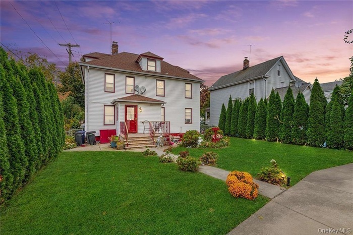 Back of property at dusk featuring a lawn and a chimney