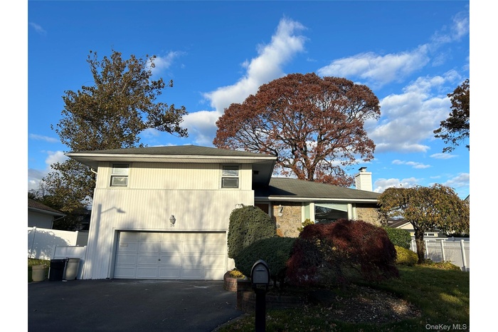 View of front of home with a garage, driveway, a chimney, and stone siding
