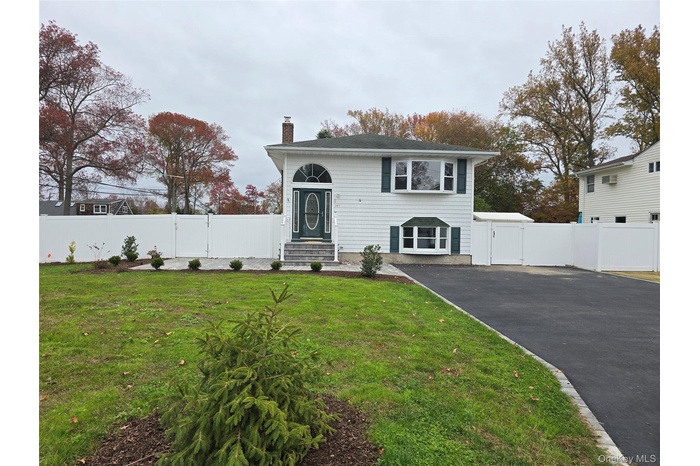 View of front facade with a gate, a chimney, and driveway