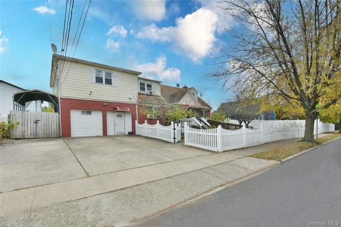 View of front of house with a fenced front yard, brick siding, a gate, concrete driveway, and an attached garage