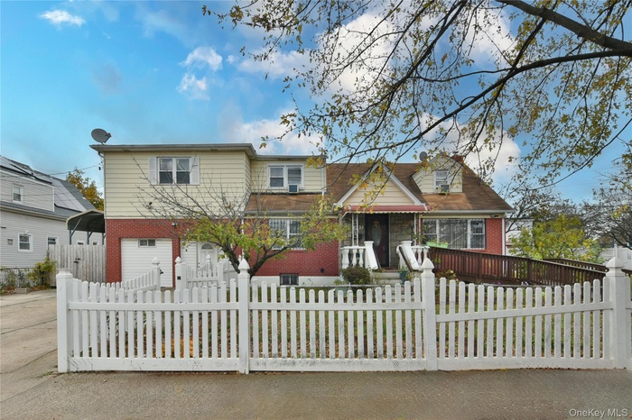 Traditional home featuring brick siding, a garage, a fenced front yard, and driveway