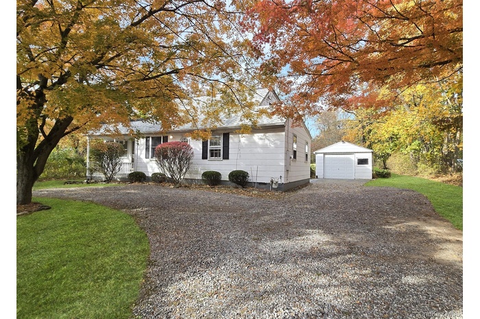 View of front of property featuring an outdoor structure, a front yard, a garage, and driveway