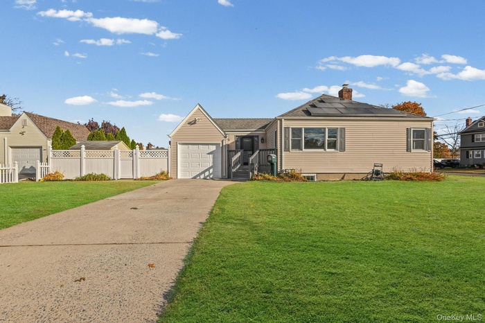 View of front of house with concrete driveway, roof mounted solar panels, a chimney, and a garage