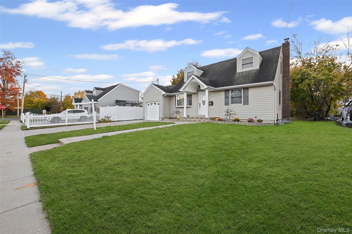 Cape cod-style house with a chimney, a shingled roof, and driveway