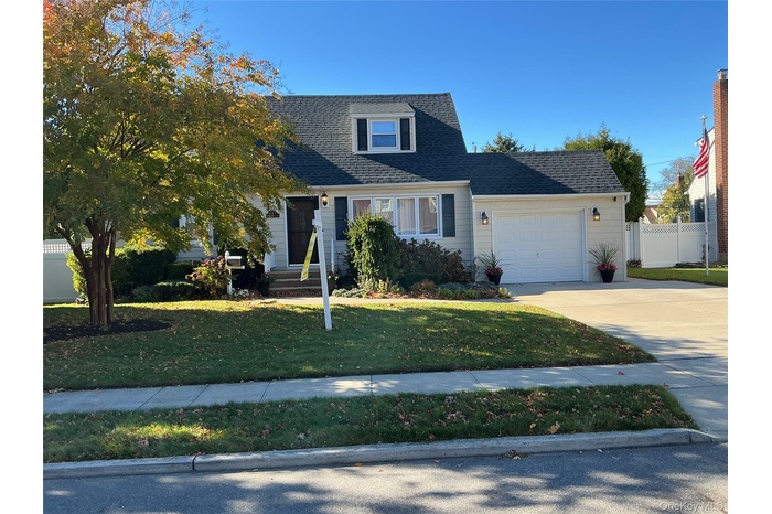 View of front of house featuring an attached garage, driveway, and a shingled roof