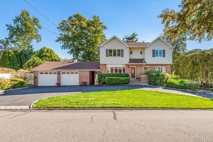 Traditional-style house featuring brick siding, driveway, an attached garage, and a front lawn