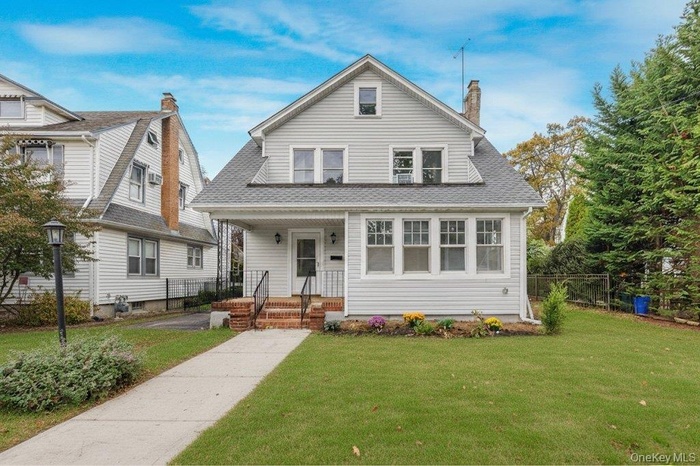 View of front of property with roof with shingles, covered porch, and a chimney