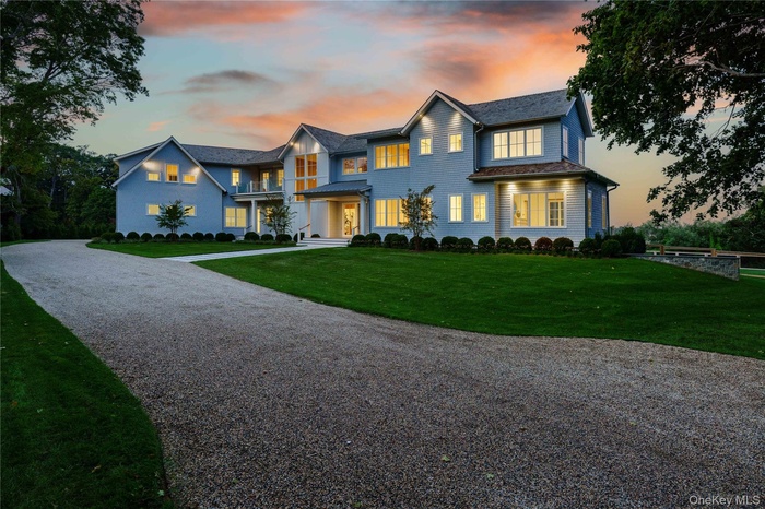 View of front of property with driveway, a yard, and a balcony