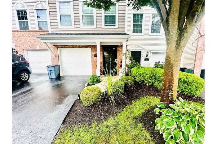 View of front facade with asphalt driveway, brick siding, and an attached garage