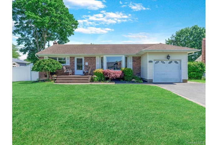 Ranch-style house with an attached garage, asphalt driveway, a chimney, and roof with shingles