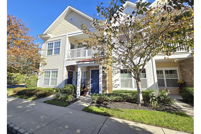 End Unit View of front of home featuring a balcony and stone siding