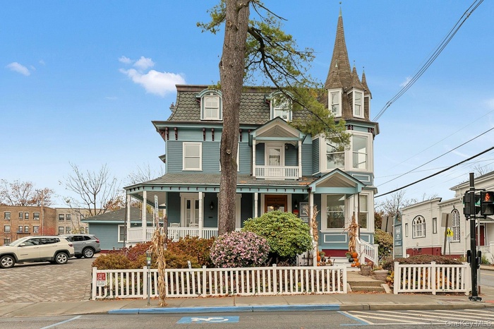 View of front facade with a fenced front yard, a porch, and mansard roof