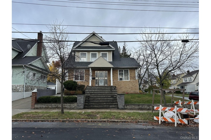 View of front of property featuring brick siding and roof with shingles