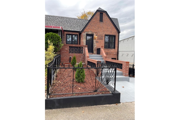 View of front of home featuring a shingled roof, brick siding, and a fenced front yard