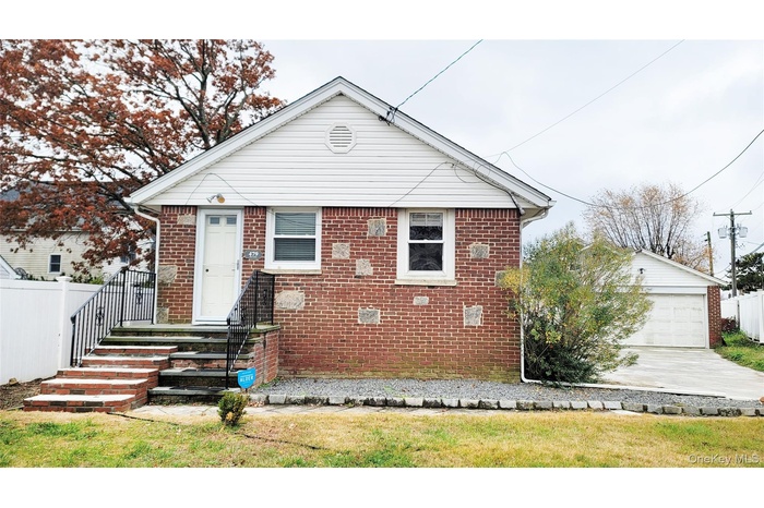 View of front of home featuring a garage, brick siding, and an outdoor structure