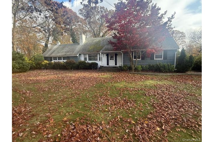 View of front facade featuring a chimney, a front lawn, and covered porch