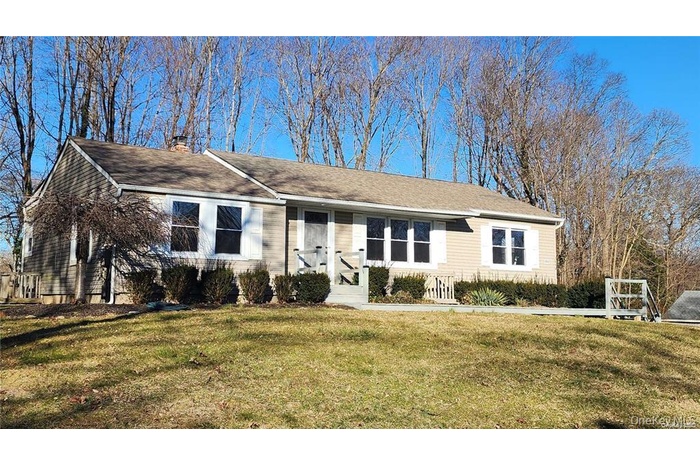 View of front of home with a front lawn, a chimney, and a shingled roof