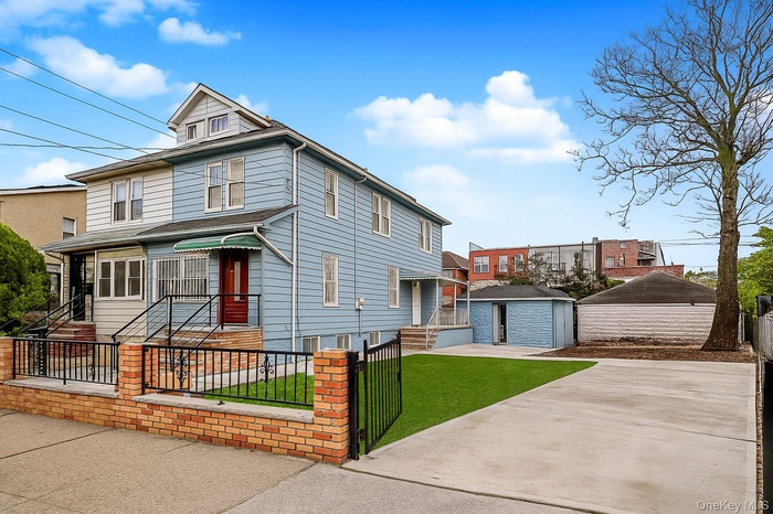 American foursquare style home featuring a fenced front yard, an outdoor structure, and a patio area