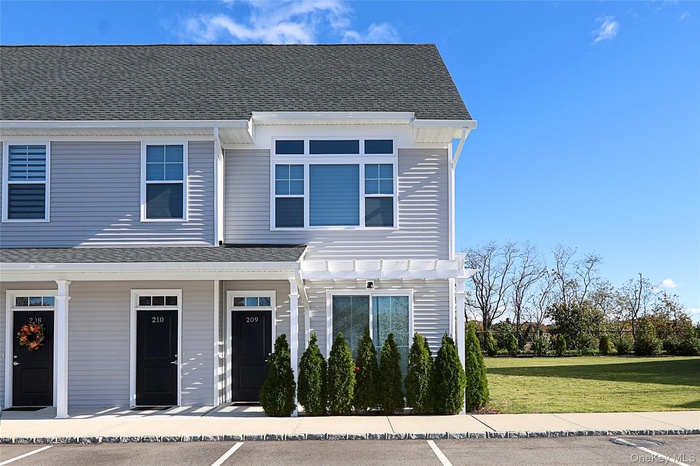 View of front of property featuring a shingled roof, a front yard, and covered porch