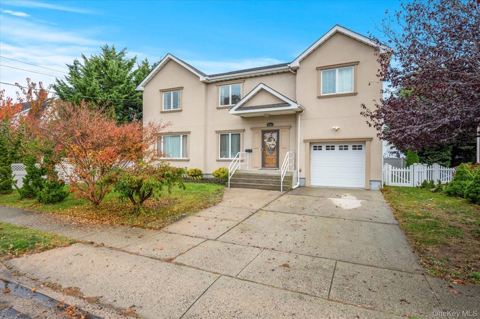 Traditional home with stucco siding, concrete driveway, an attached garage, and a gate