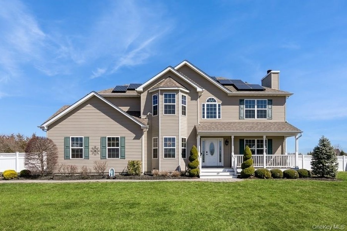Traditional-style home with covered porch, a chimney, and roof mounted solar panels