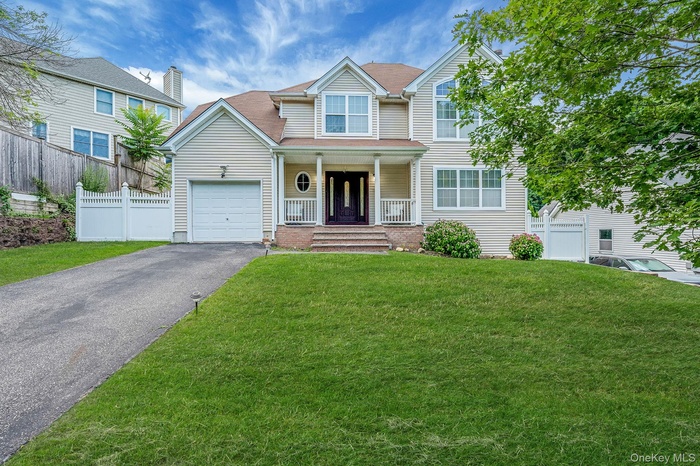 Traditional-style house with covered porch, asphalt driveway, and an attached garage